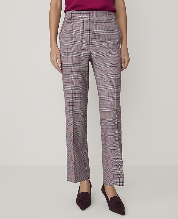 A person wearing a magenta top, plaid trousers, and dark purple heels stands against a plain white background.