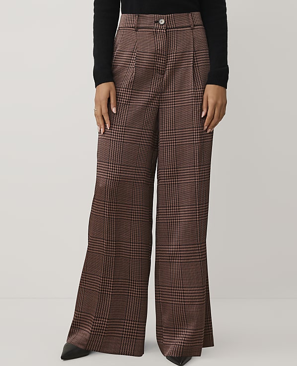 A person wears brown plaid wide-leg trousers and a black top against a plain white background.
