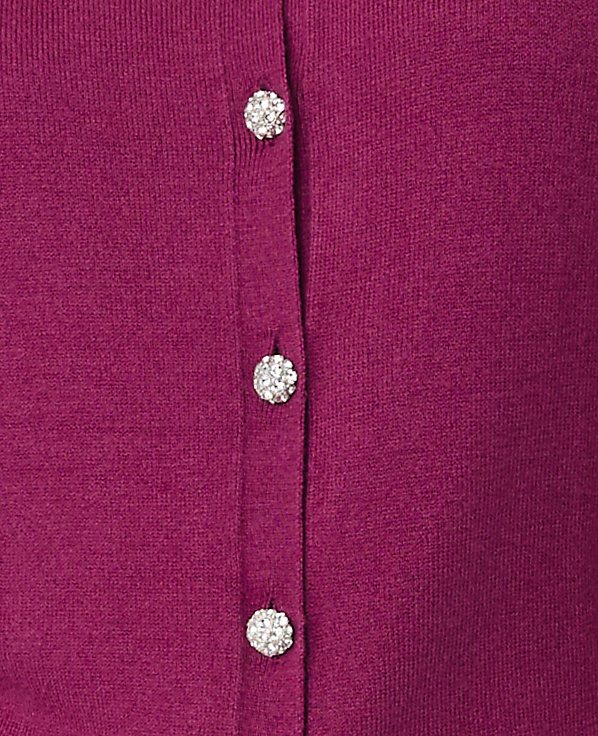 Three sparkling rhinestone buttons are aligned vertically on a magenta knit fabric.
