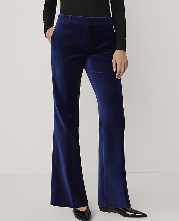 A person wears royal blue velvet flared trousers and a black top against a plain light grey background.