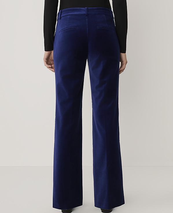 A person wearing a black top and wide-leg royal blue velvet trousers stands against a plain light gray background.