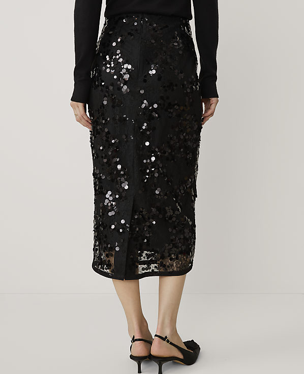 A person wearing a black sequined midi skirt and black heels stands against a plain white background.
