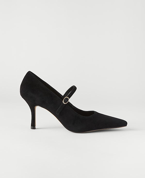 A black suede pointed-toe pump with a gold buckle strap sits against a plain, light grey background.