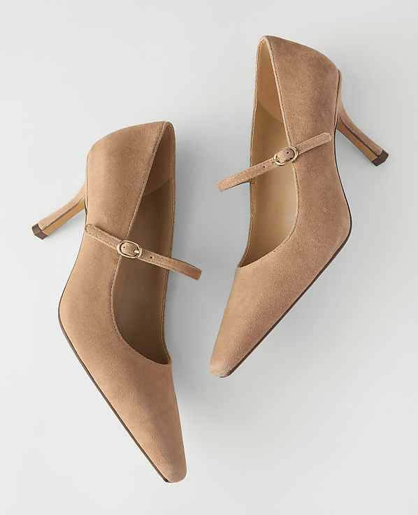 A pair of tan suede pointed-toe pumps with ankle straps rests on a plain white background.