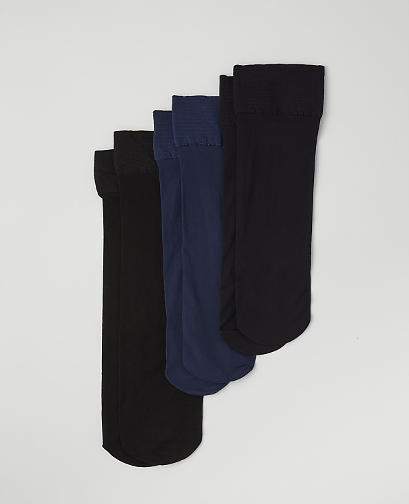 Four pairs of black and navy blue socks are arranged in a staggered row against a plain light gray background.
