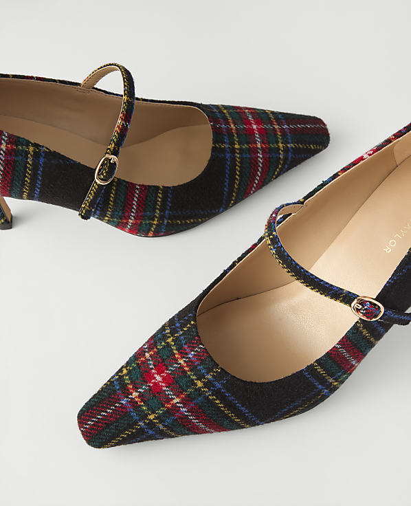 A pair of pointed-toe plaid pumps with ankle straps rests on a plain white background.