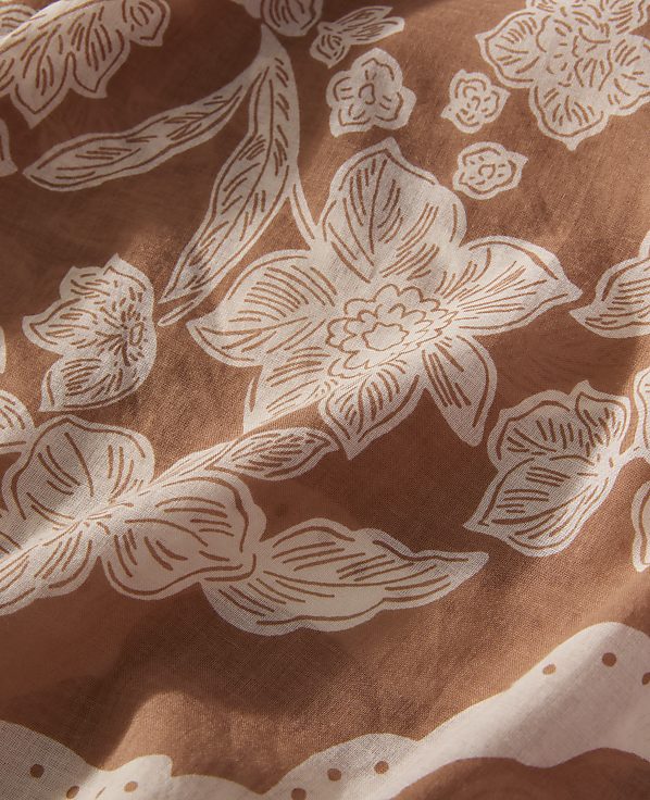 White floral patterns are printed across a textured, rust-brown fabric background.
