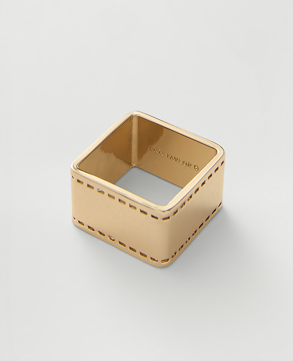 A gold-toned metal ring secures a blue, white, and black striped silk scarf against a plain light gray background.