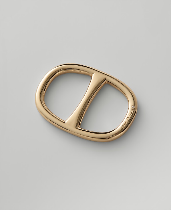A blue, black, and beige patterned fabric is looped through a gold-toned oval buckle against a plain light gray background.