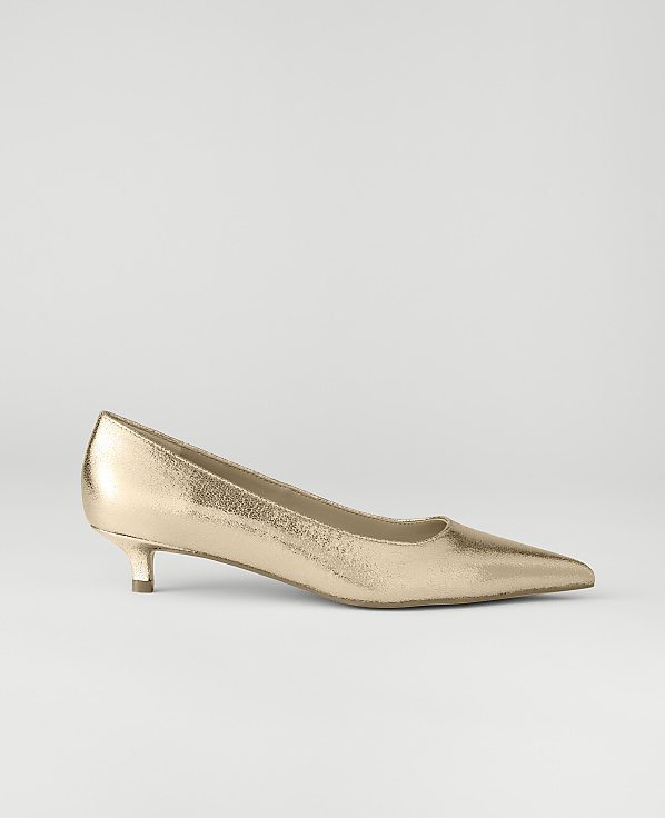 A metallic rose-gold pointed-toe pump sits in the foreground against a plain, light gray background.