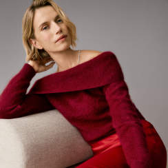 Woman in a red cashmere sweater lounging on a sofa