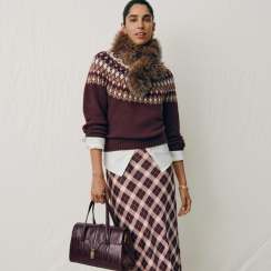 Woman in a Fair Isle sweater, plaid skirt and burgundy bag