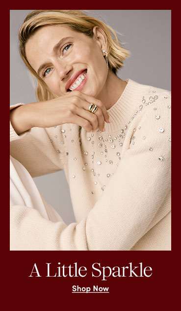 A smiling woman in a sparkling cream sweater against a light background.