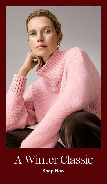 A woman in a pink turtleneck sweater and brown pants against a grey background.
