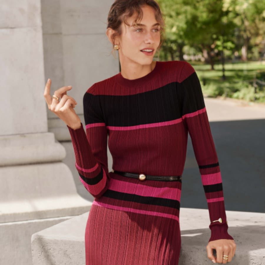Woman in a berry and pink striped sweater and pleated skirt