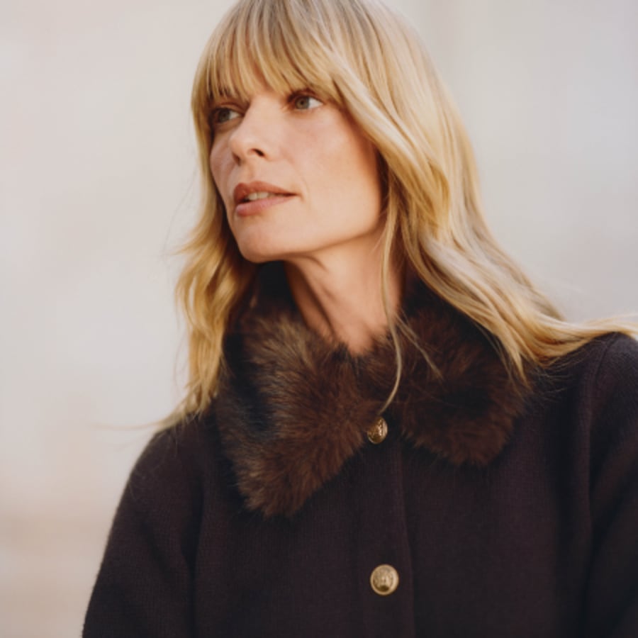 Woman in a dark chocolate cardigan with a faux fur collar