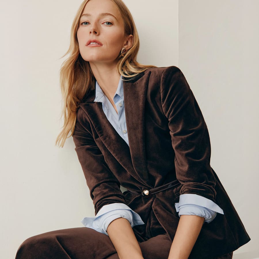 Woman in a brown velvet blazer over a light blue shirt