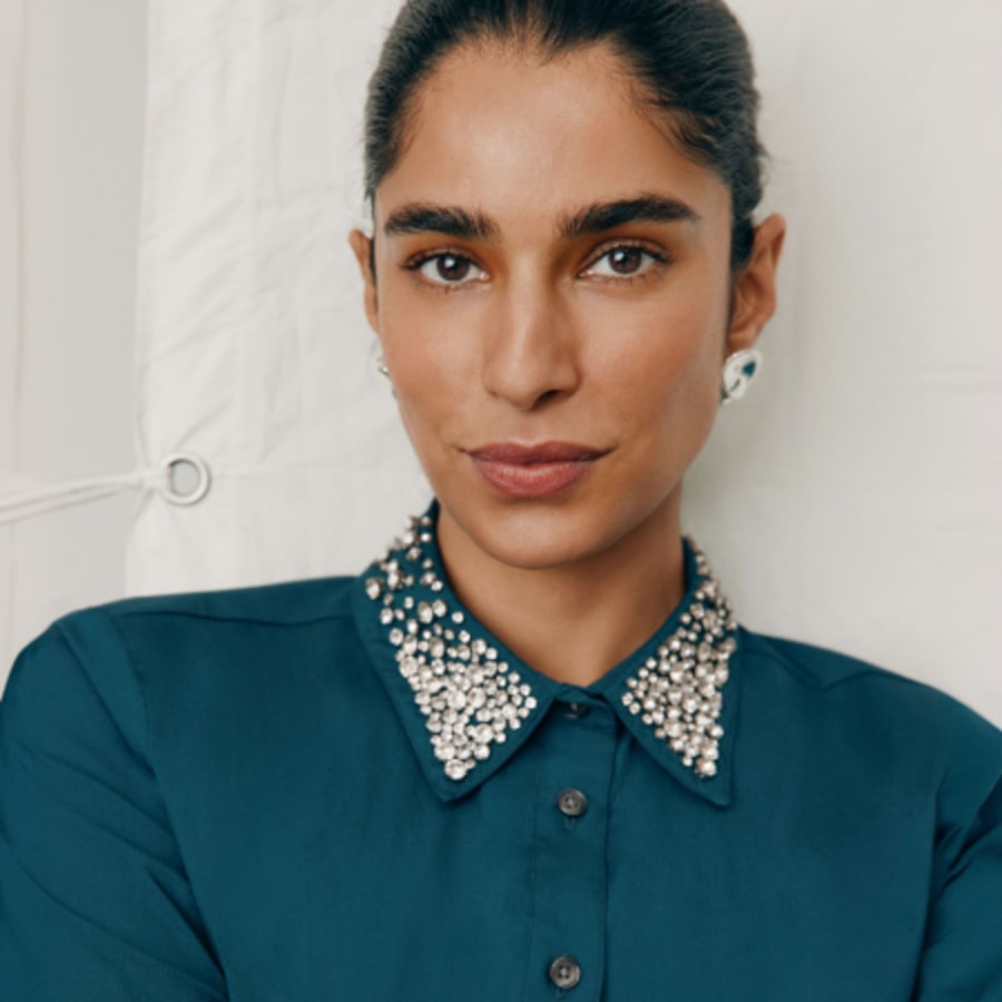 Woman in a rich teal shirt with a crystal-embellished collar