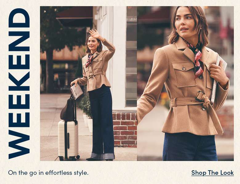 On the go in effortless style — woman in a tan belted jacket and jeans with a suitcase in the city. Shop the Look.